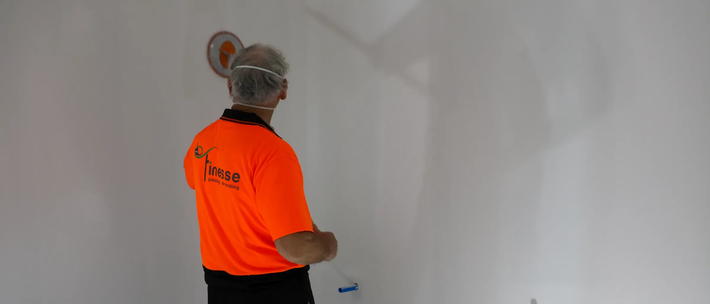 A Finesse painter in branded hi-vis rolling out a freshly stopped interior wall