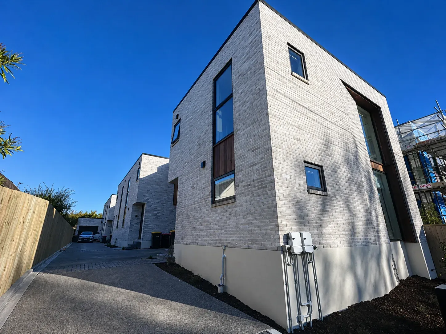 Newly finished townhouses at 4 Hurley Street, white brick and dark-framed windows along a shared driveway