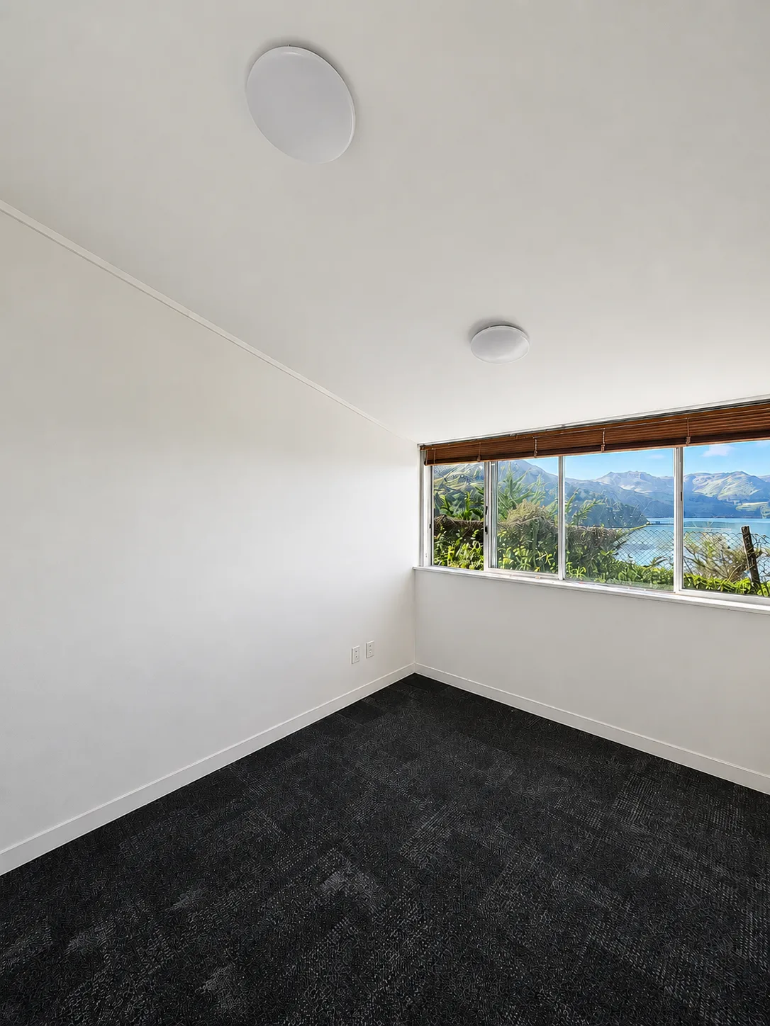 A bedroom at Cholmondeley Children's Centre, pale walls and a timber-framed window looking out over the harbour