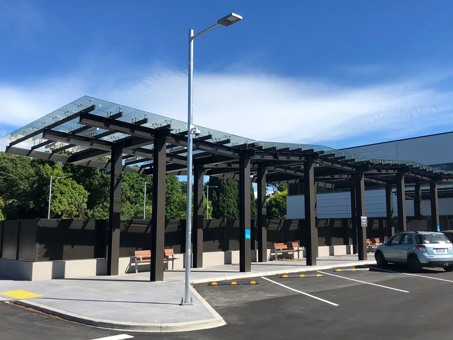 Painted structural steel canopies over the car park at Christchurch Hospital, glass roofing above dark coated beams and columns