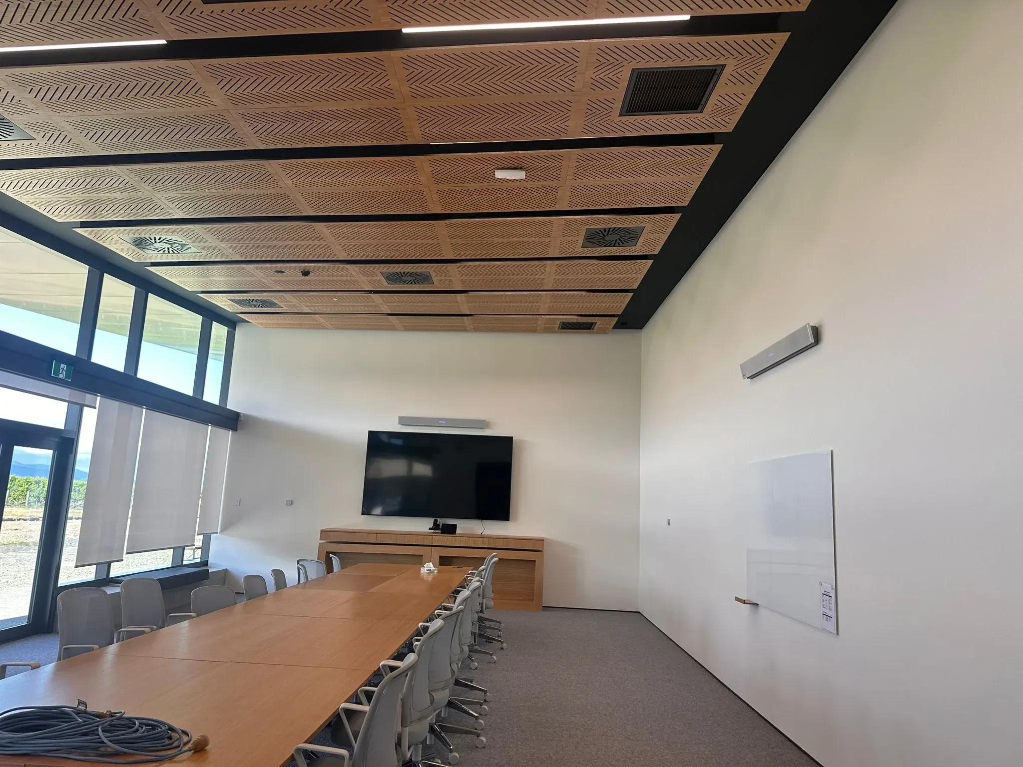The Delegat Winery boardroom, pale walls beneath a perforated timber acoustic ceiling, with vineyard views through the glazing