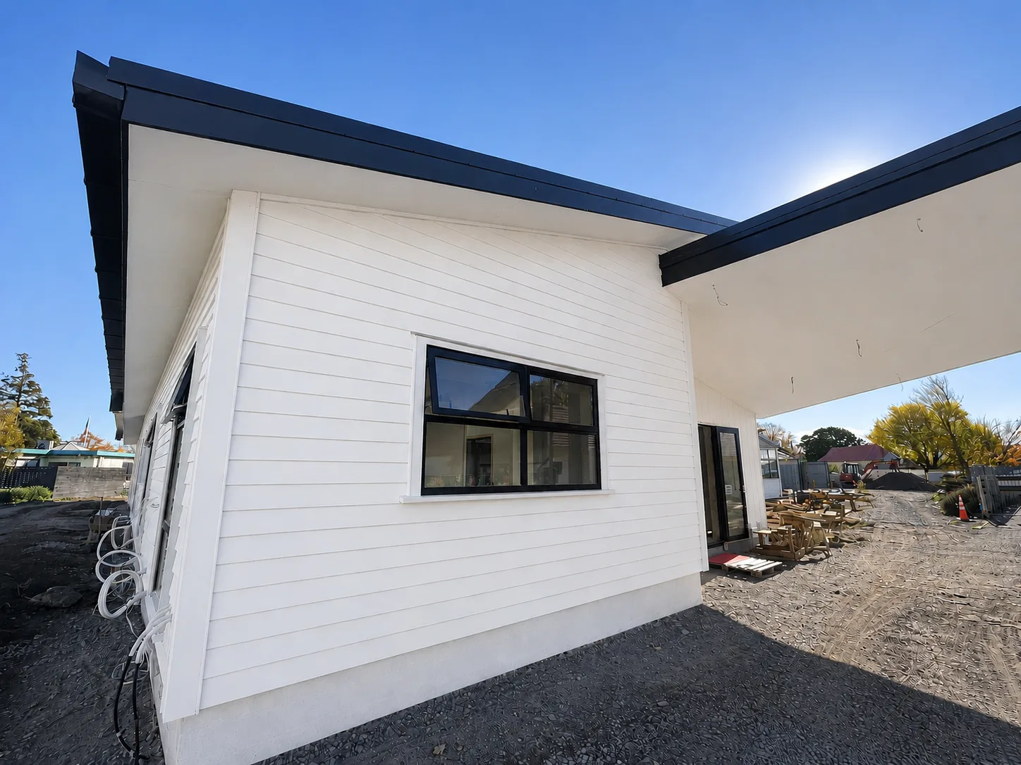 A white weatherboard elevation at St Mary's School under a dark fascia and soffit, with the covered walkway alongside