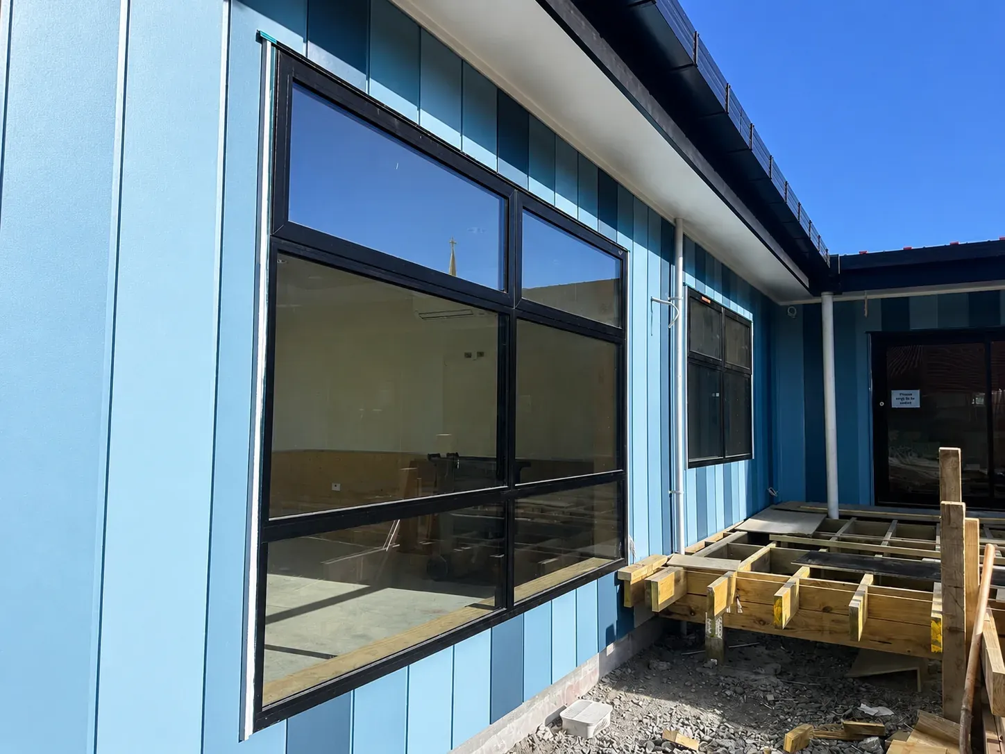 The exterior of St Mary's School, blue Stria vertical feature boards with black-framed windows under a clear sky
