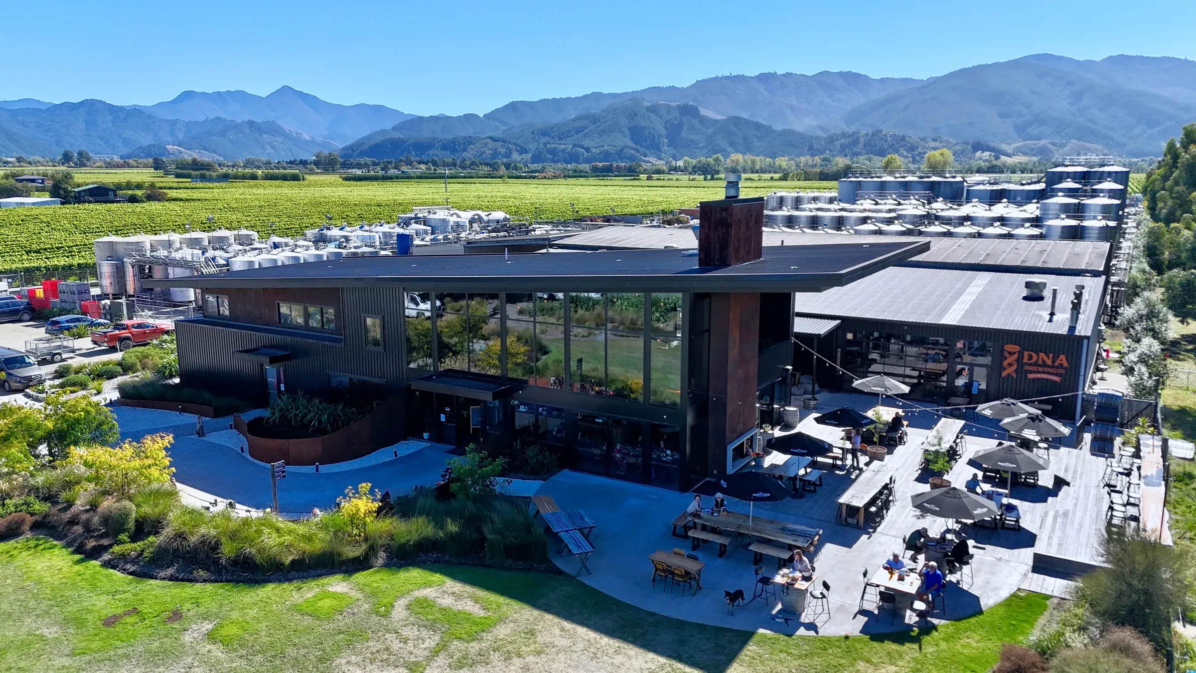 The Fancy Cow from the air, a dark building with a rust-effect chimney set among Marlborough vineyards