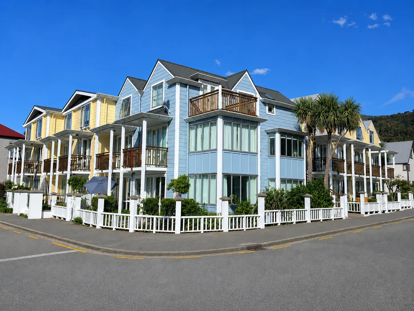 Bruce Waterfront Apartments in Akaroa, a blue and yellow weatherboard development with white balustrades on the harbour front